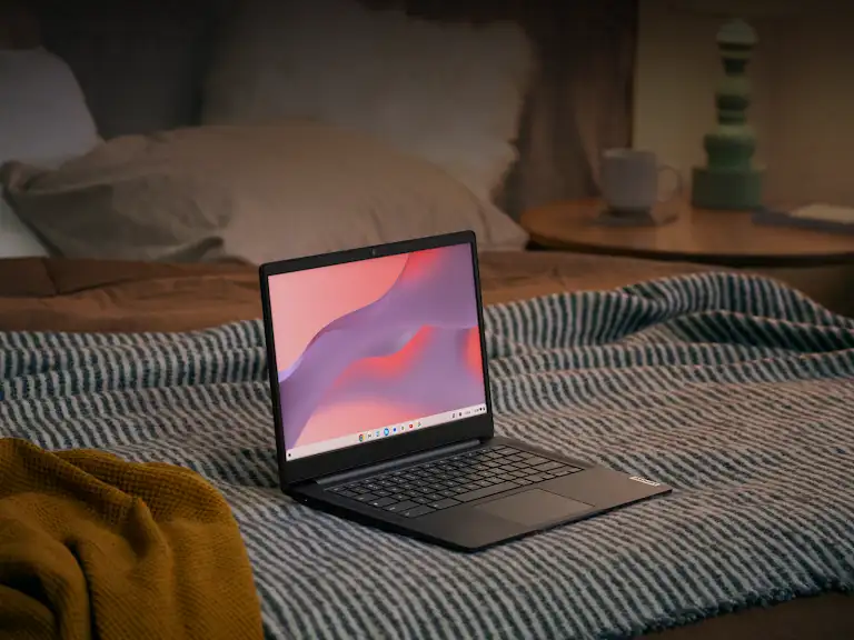 Image of a Chromebook laptop sat open on a bed.