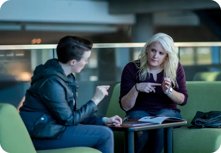 Two women have a conversation using sign language discussing a magazine article.